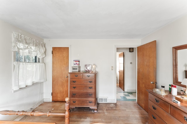 bedroom with visible vents, baseboards, and wood finished floors