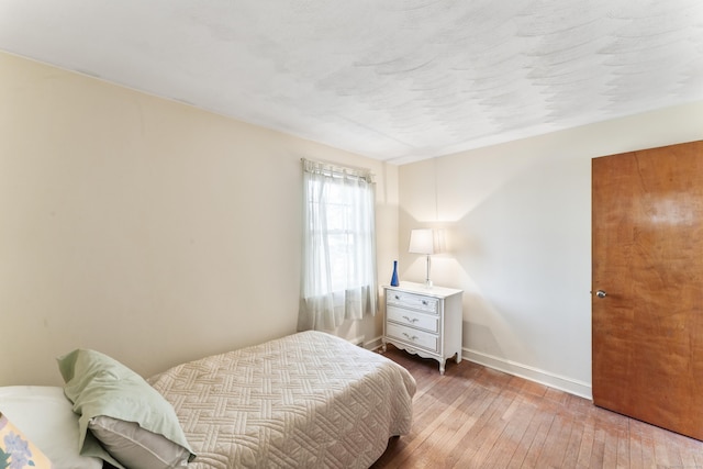 bedroom with light wood-type flooring and baseboards