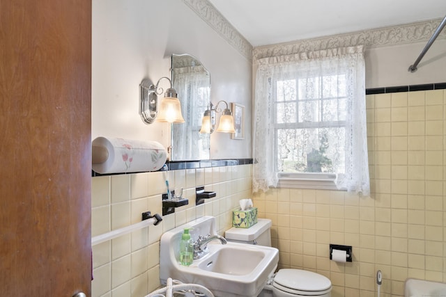 full bath featuring toilet, walk in shower, a sink, and tile walls