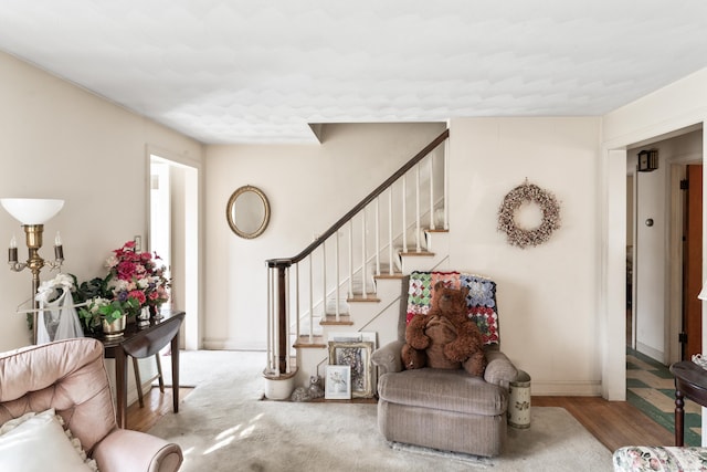 living area featuring baseboards, stairway, and wood finished floors