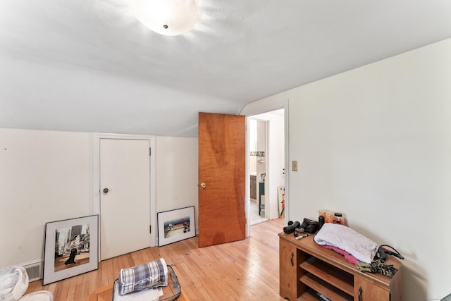 interior space featuring light wood-style flooring, vaulted ceiling, and visible vents