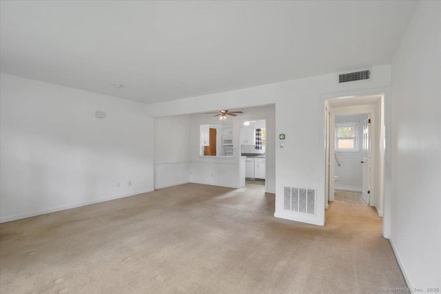 empty room with light carpet, a ceiling fan, and baseboards