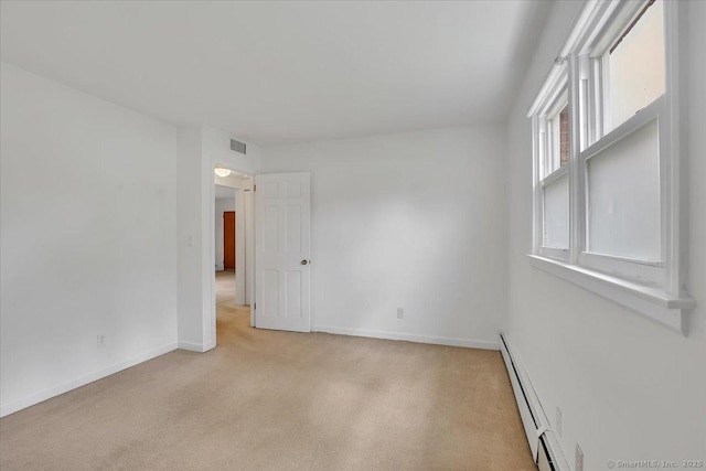 unfurnished room with baseboard heating, light carpet, and baseboards