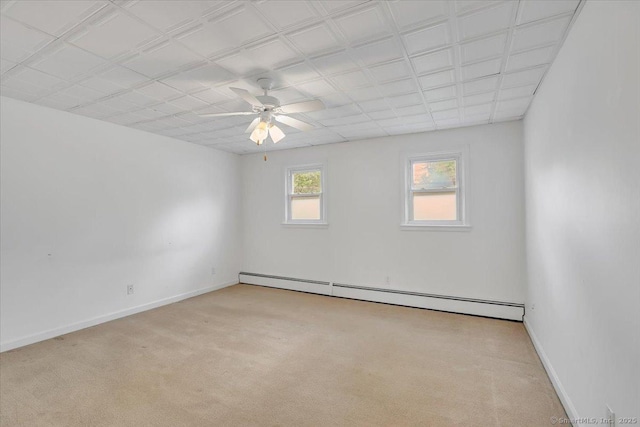 spare room with baseboard heating, carpet flooring, ceiling fan, and baseboards