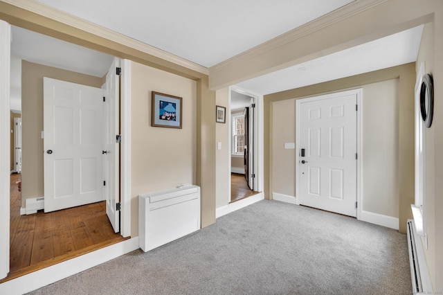 carpeted foyer with baseboards, ornamental molding, and a baseboard radiator