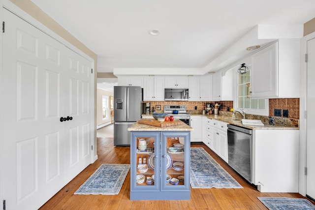 kitchen with tasteful backsplash, white cabinets, appliances with stainless steel finishes, and a kitchen island