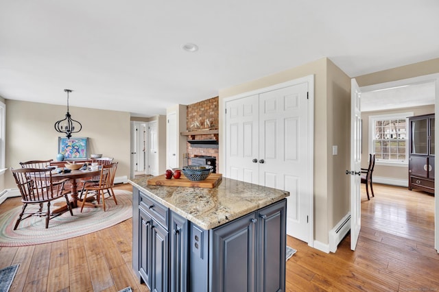 kitchen featuring light wood-style floors, a center island, baseboards, pendant lighting, and a baseboard radiator