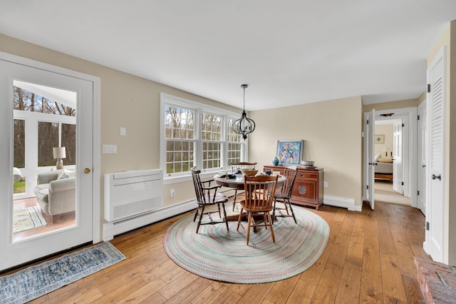 dining area featuring light wood-type flooring, baseboard heating, and baseboards