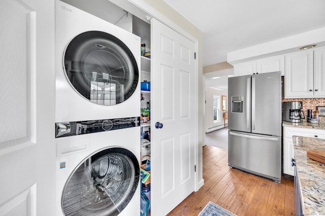 clothes washing area featuring light wood-type flooring, stacked washer / drying machine, and laundry area