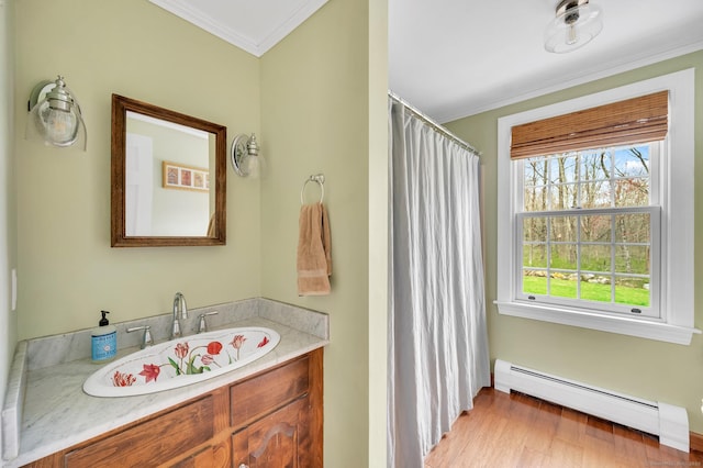 bathroom with wood finished floors, a baseboard heating unit, a shower with curtain, vanity, and crown molding
