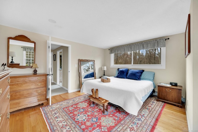 bedroom featuring light wood-type flooring and a baseboard heating unit