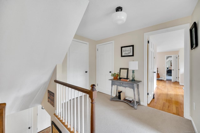 hallway with an upstairs landing, carpet floors, and baseboards