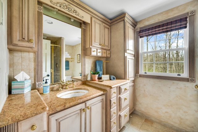 bathroom featuring a stall shower, vanity, and baseboards
