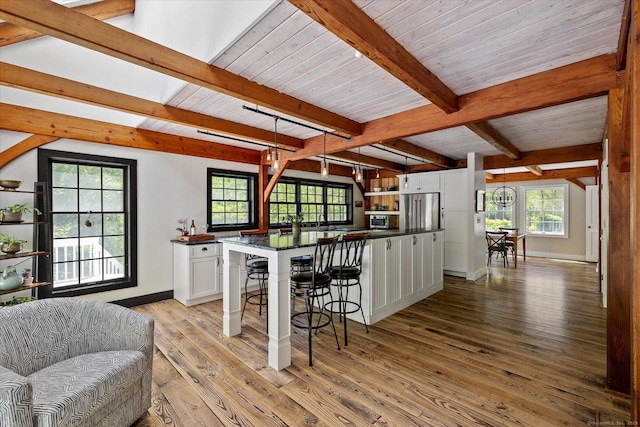 128 Spaulding Rd, Brooklyn, CT 06234 - kitchen with dark countertops, white cabinetry, a kitchen bar, light wood finished floors, and beamed ceiling