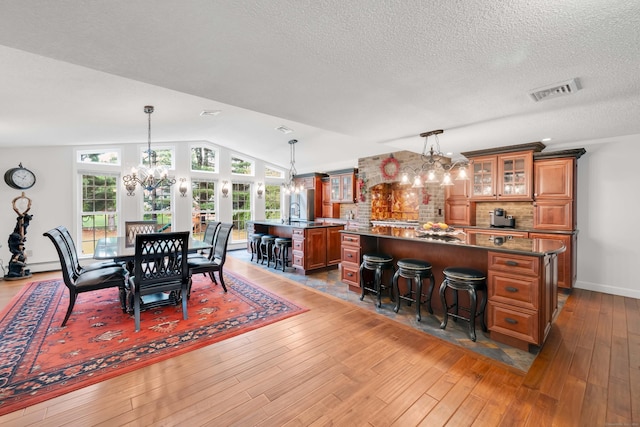 340 Brookfield St, South Windsor, CT 06074 - dining space with a chandelier, hardwood / wood-style flooring, vaulted ceiling, a textured ceiling, and baseboard heating