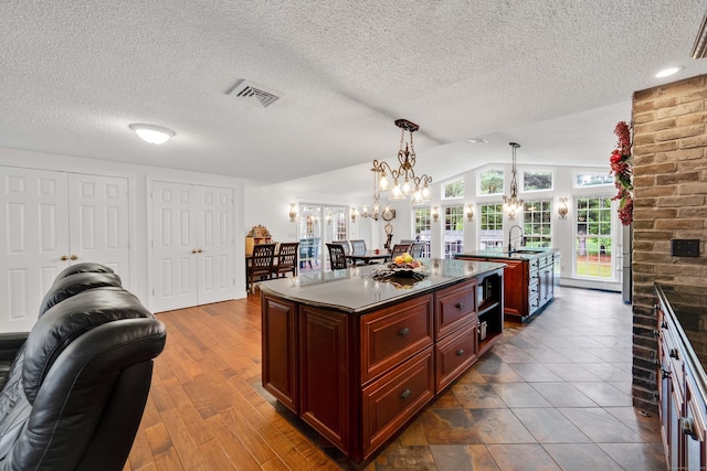 340 Brookfield St, South Windsor, CT 06074 - kitchen featuring an island with sink, dark countertops, a sink, dark brown cabinets, and a chandelier
