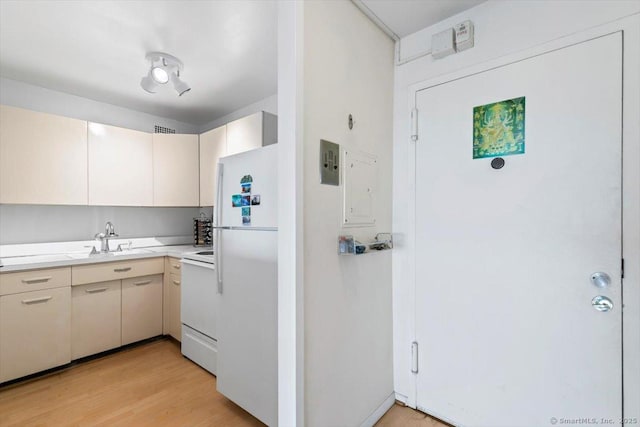 kitchen featuring electric panel, a sink, light countertops, freestanding refrigerator, and range