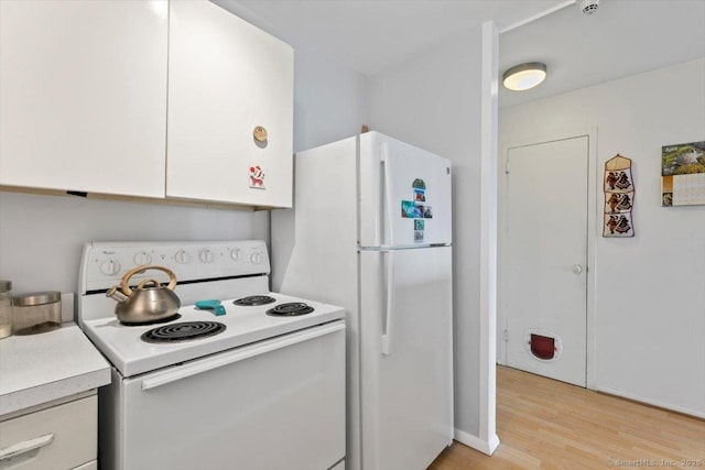 kitchen with light wood-style flooring, light countertops, white appliances, and white cabinets