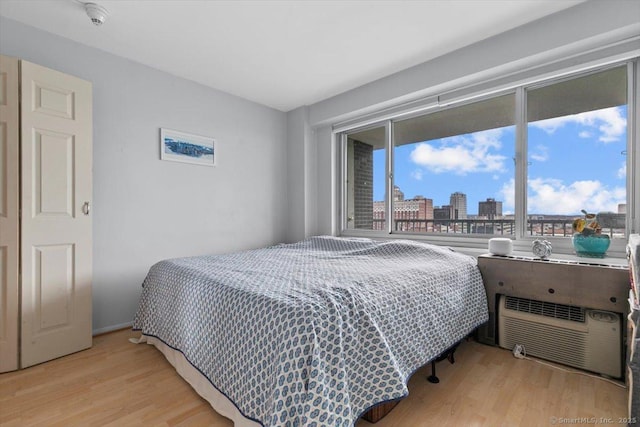 bedroom featuring a wall mounted air conditioner, a view of city, and wood finished floors