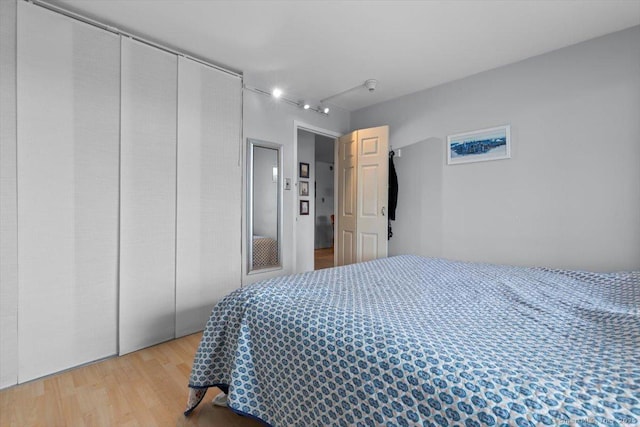 bedroom featuring track lighting and wood finished floors