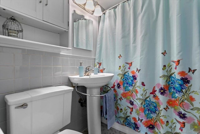 full bathroom featuring toilet, curtained shower, tasteful backsplash, and tile walls
