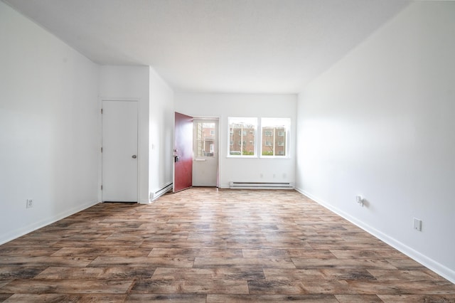unfurnished room with a baseboard radiator, baseboards, and wood finished floors