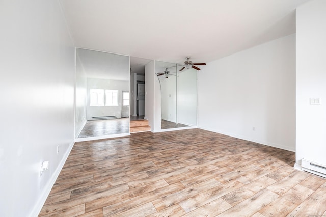 unfurnished room with a baseboard radiator, a ceiling fan, wood finished floors, and baseboards