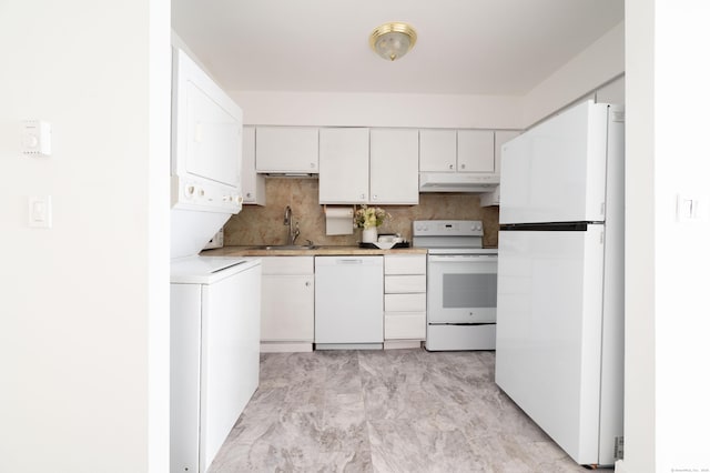 kitchen with a sink, light countertops, white appliances, stacked washer / drying machine, and under cabinet range hood