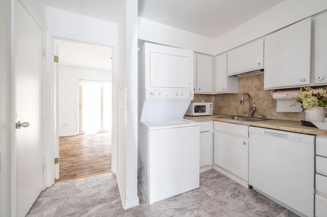 washroom with laundry area, stacked washer and clothes dryer, and a sink