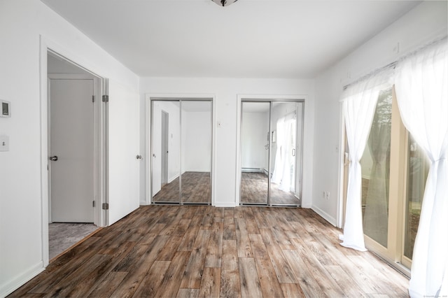 unfurnished bedroom featuring two closets and wood finished floors