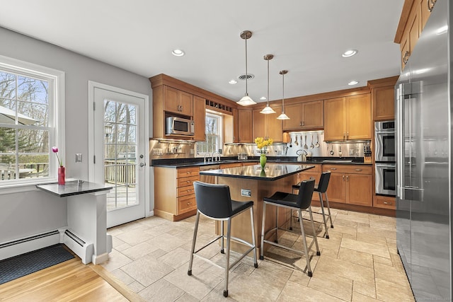 181 Picketts Ridge Rd, Redding, CT 06896 - kitchen featuring appliances with stainless steel finishes, dark countertops, brown cabinetry, a kitchen bar, and recessed lighting
