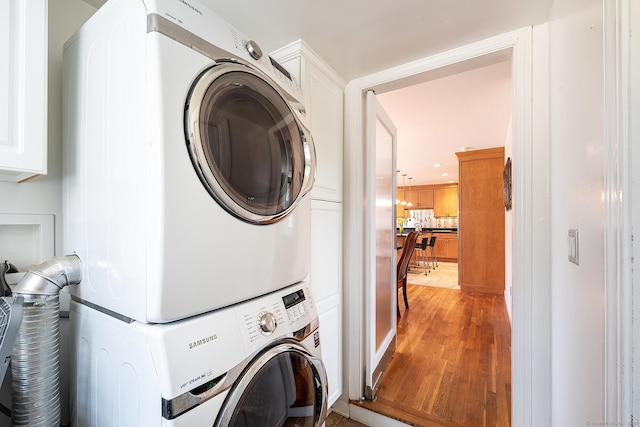 181 Picketts Ridge Rd, Redding, CT 06896 - laundry room featuring estacked washer and dryer, light wood-style floors, and cabinet space