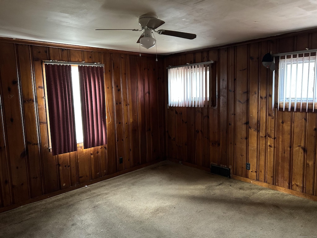 83 Pearl Harbor Cir, Bridgeport, CT 06610 - carpeted spare room with wood walls, visible vents, ceiling fan, and plenty of natural light