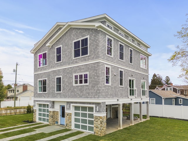 view of front of property featuring a front lawn, fence, stone siding, and a garage