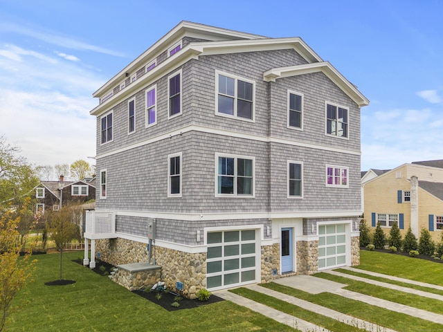 shingle-style home with driveway, stone siding, a front yard, and a garage
