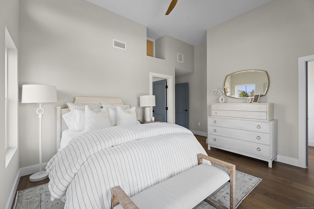 bedroom with dark wood finished floors, baseboards, a high ceiling, and visible vents