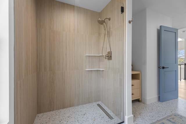 full bathroom featuring baseboards, speckled floor, and a tile shower