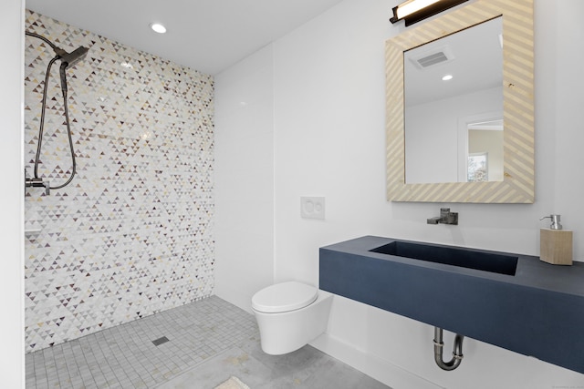 bathroom with a sink, a tile shower, toilet, visible vents, and recessed lighting