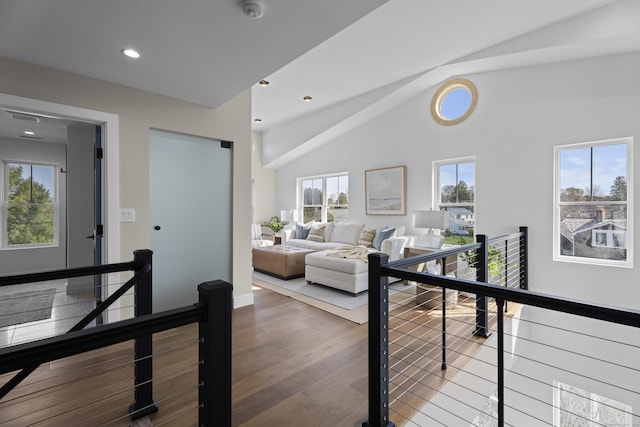 interior space with high vaulted ceiling, wood finished floors, an upstairs landing, and recessed lighting