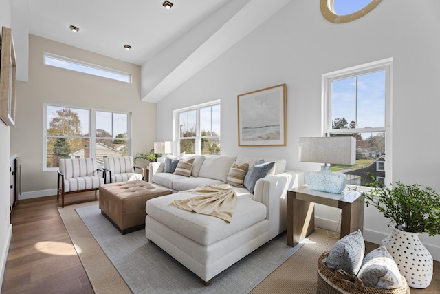 living room featuring a towering ceiling, wood finished floors, and baseboards
