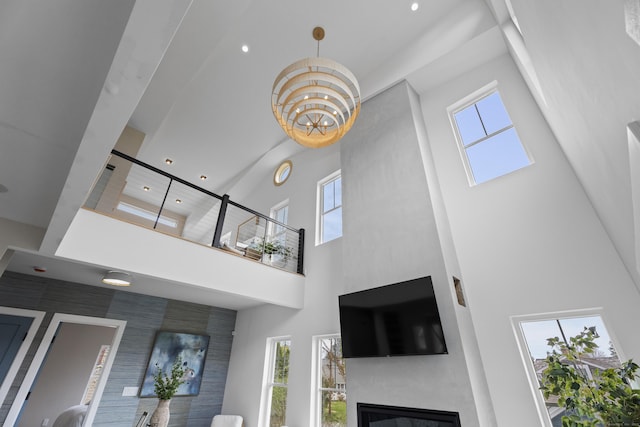 interior space featuring a glass covered fireplace, a towering ceiling, and recessed lighting