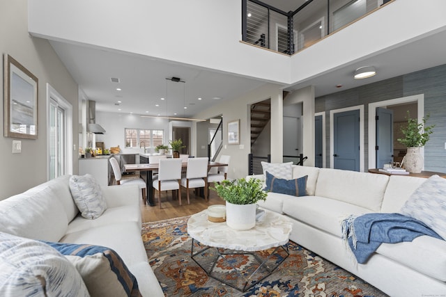 living area featuring visible vents, a towering ceiling, recessed lighting, wood finished floors, and stairs
