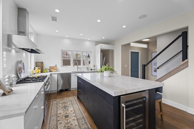 kitchen featuring a center island, visible vents, modern cabinets, exhaust hood, and beverage cooler