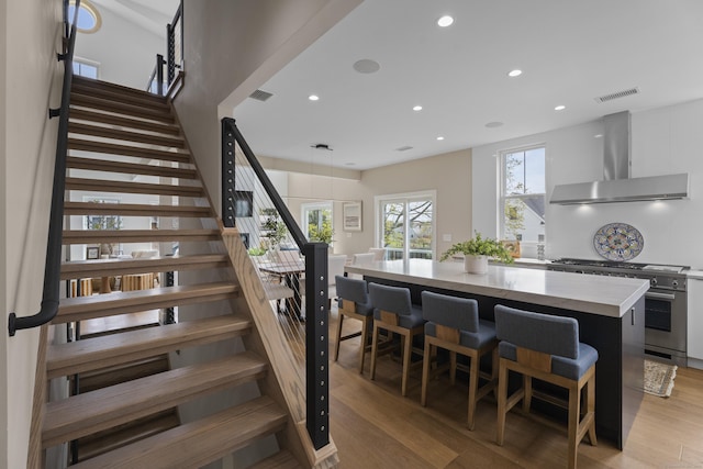 staircase featuring wood finished floors, visible vents, and recessed lighting