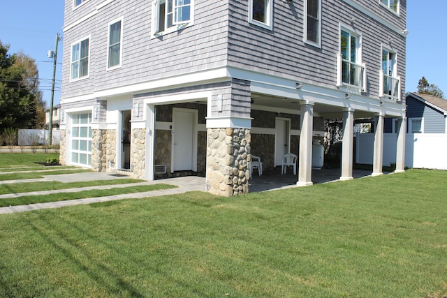 exterior space with fence, a front lawn, and stone siding