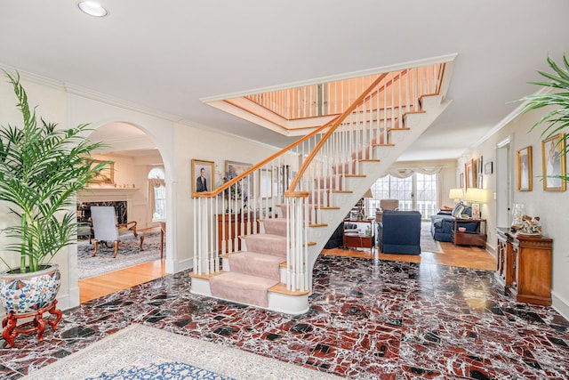 stairs featuring crown molding, arched walkways, baseboards, and recessed lighting