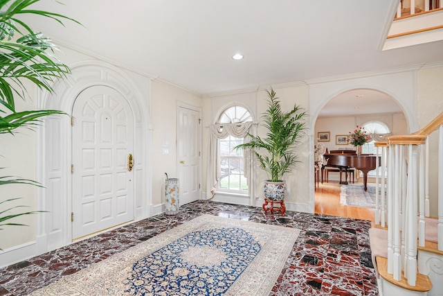 entryway featuring ornamental molding, marble finish floor, baseboards, recessed lighting, and arched walkways
