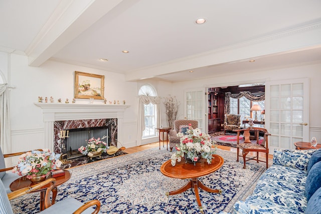 living area with crown molding, plenty of natural light, beam ceiling, and wood finished floors