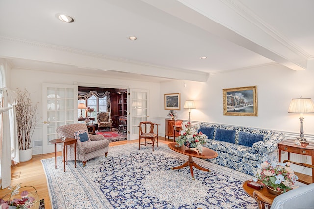 living room with ornamental molding, beamed ceiling, wainscoting, and wood finished floors