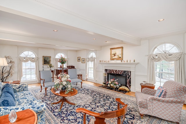 living area with a high end fireplace, beam ceiling, wood finished floors, a decorative wall, and recessed lighting